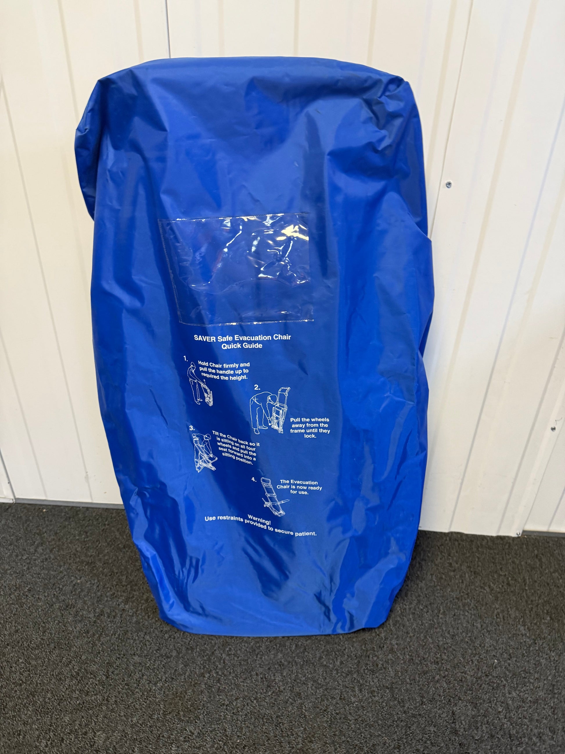 FERNO evacuation chair mounted on wall bracket with dust cover